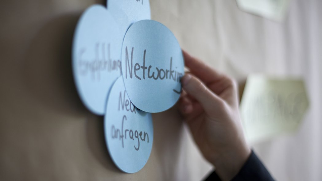 Eine Männerhand hält eine Präsentationskarte mit dem Wort "Networking" nach oben