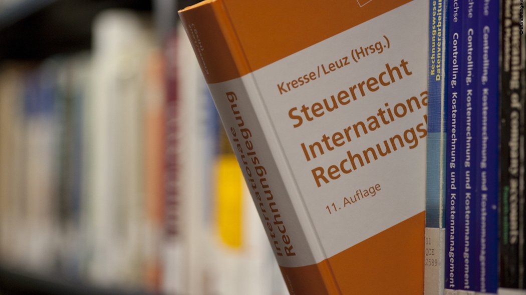 Nahaufnahme eines Buches über Steuerrecht und internationale Rechnungslegung, das aus einem Bücherregal hervorgezogen wurde.
