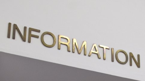 Über einer Glastür steht in goldenen Buchstaben das Wort Information.