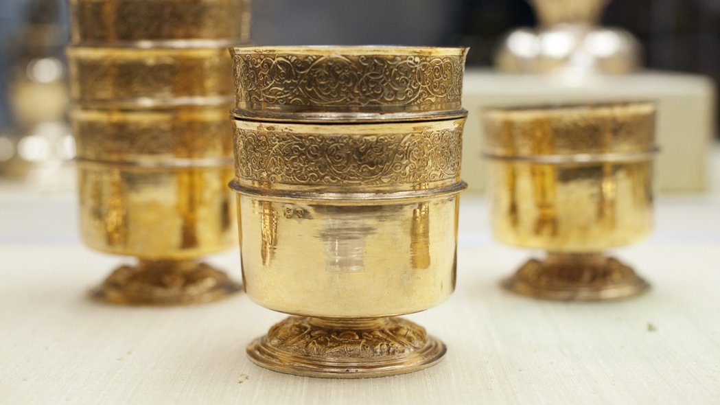 Verschiedene Goldene Kelche in unterschiedlichen Größen stehen auf einer hellen Fläche.