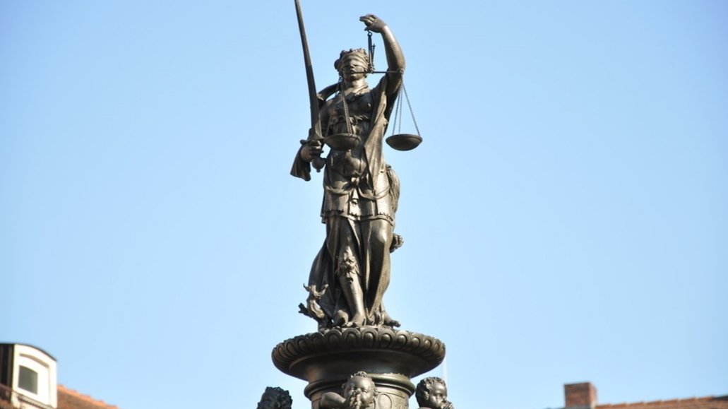 Aufnahme einer Justitia-Statue vor blauem Himmel.