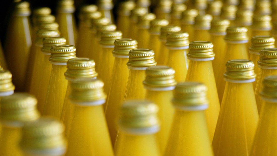 detail shot of bottles with freshly filled orange juice