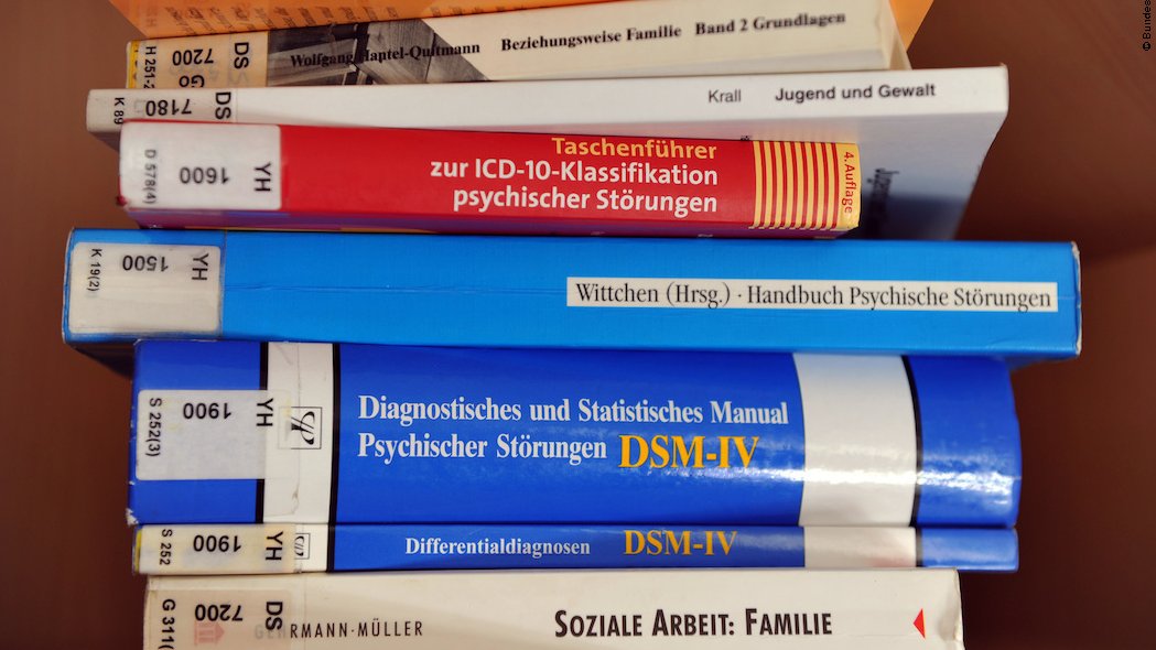 Mehrere Bücher mit Rücken unterschiedlicher Farbe und unterschiedlicher Dicke sind übereinander gestapelt. Die Themen sind Trauma-Heilung, Psychische Störungen und Soziale Arbeit.