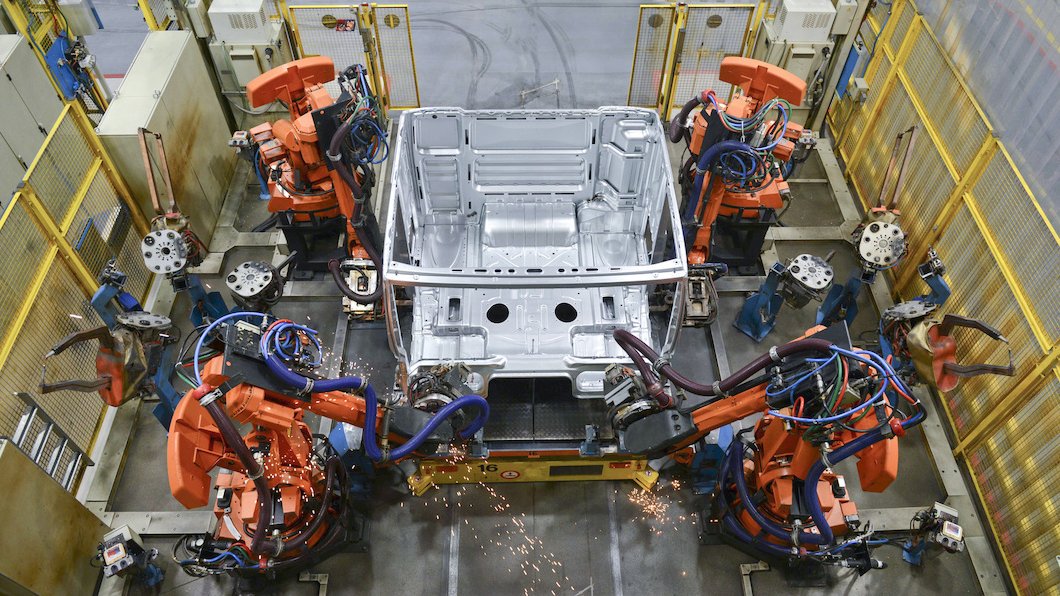 Schweißroboter arbeiten an einem Karosserieteil in einer Produktionshalle