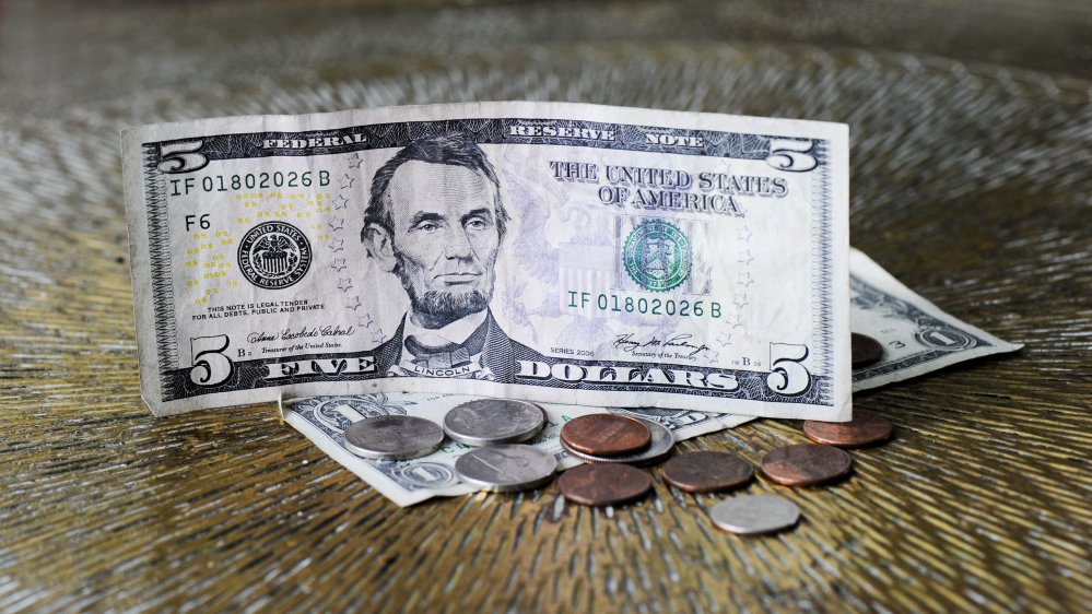pictured: A dollar note and several coins
