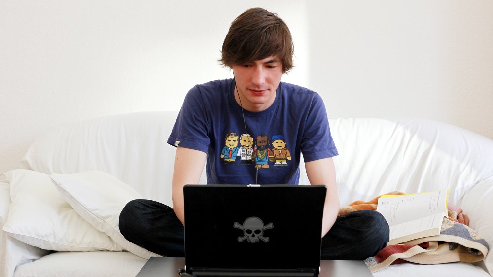 A student sitting on a couch, learning on his laptop.