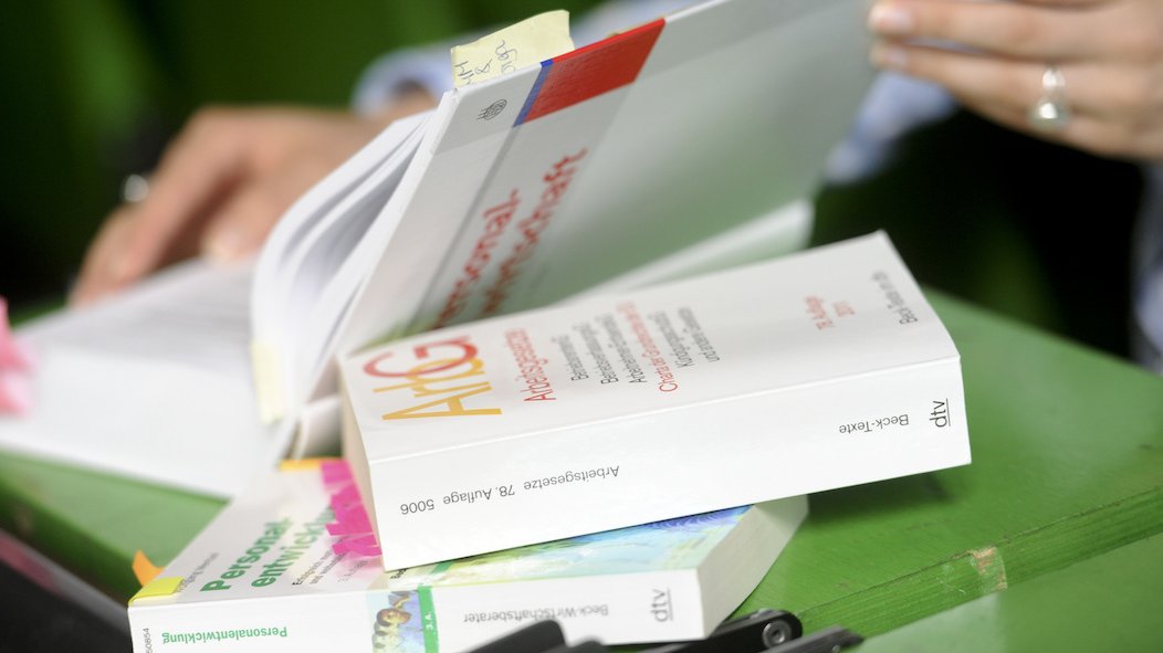 Auf einer grünen Unterlage halten zwei Frauenhände ein Buch geöffnet.