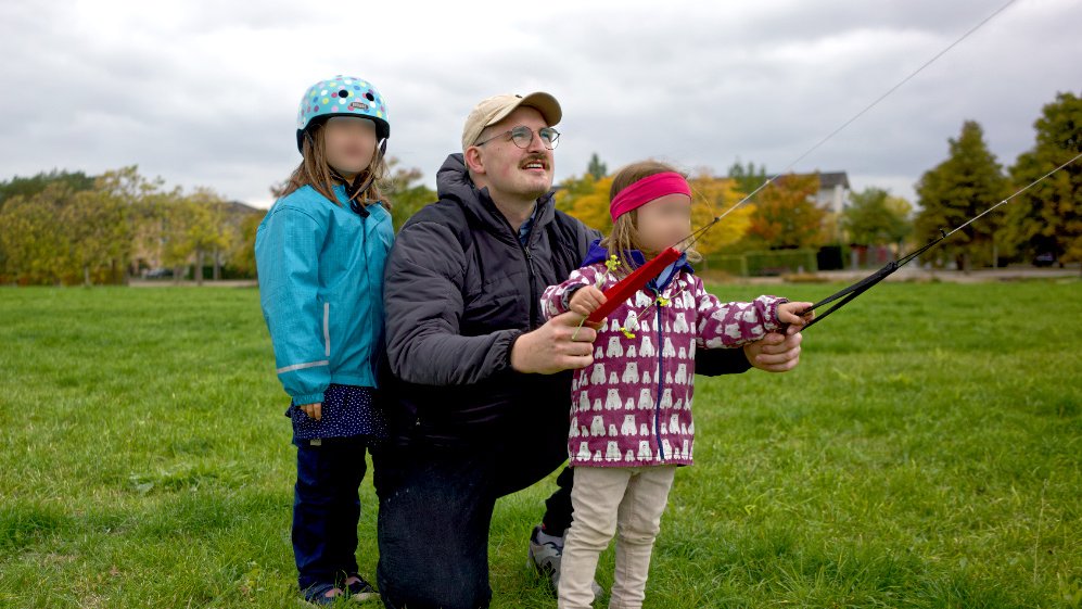 Der Student mit seinen zwei Kindern beim Drachensteigenlassen.