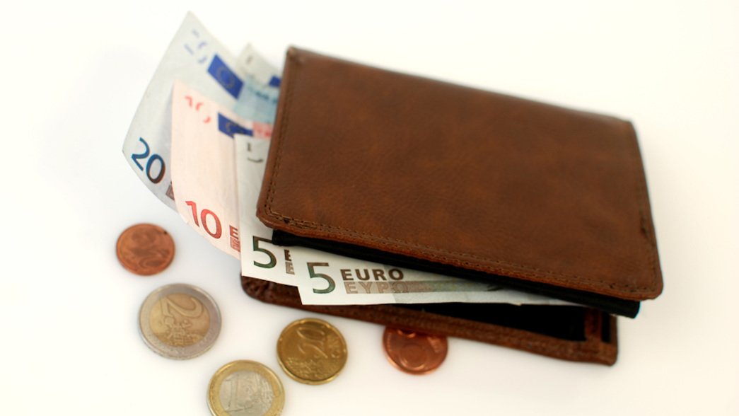 Nahaufnahme einer zugeklappten braunen Geldbörse für Herren auf hellem Untergrund.