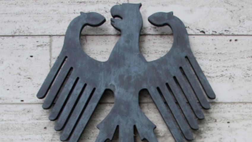 Nahaufnahme eines Bundesadlers an einer gefliesten Wand.