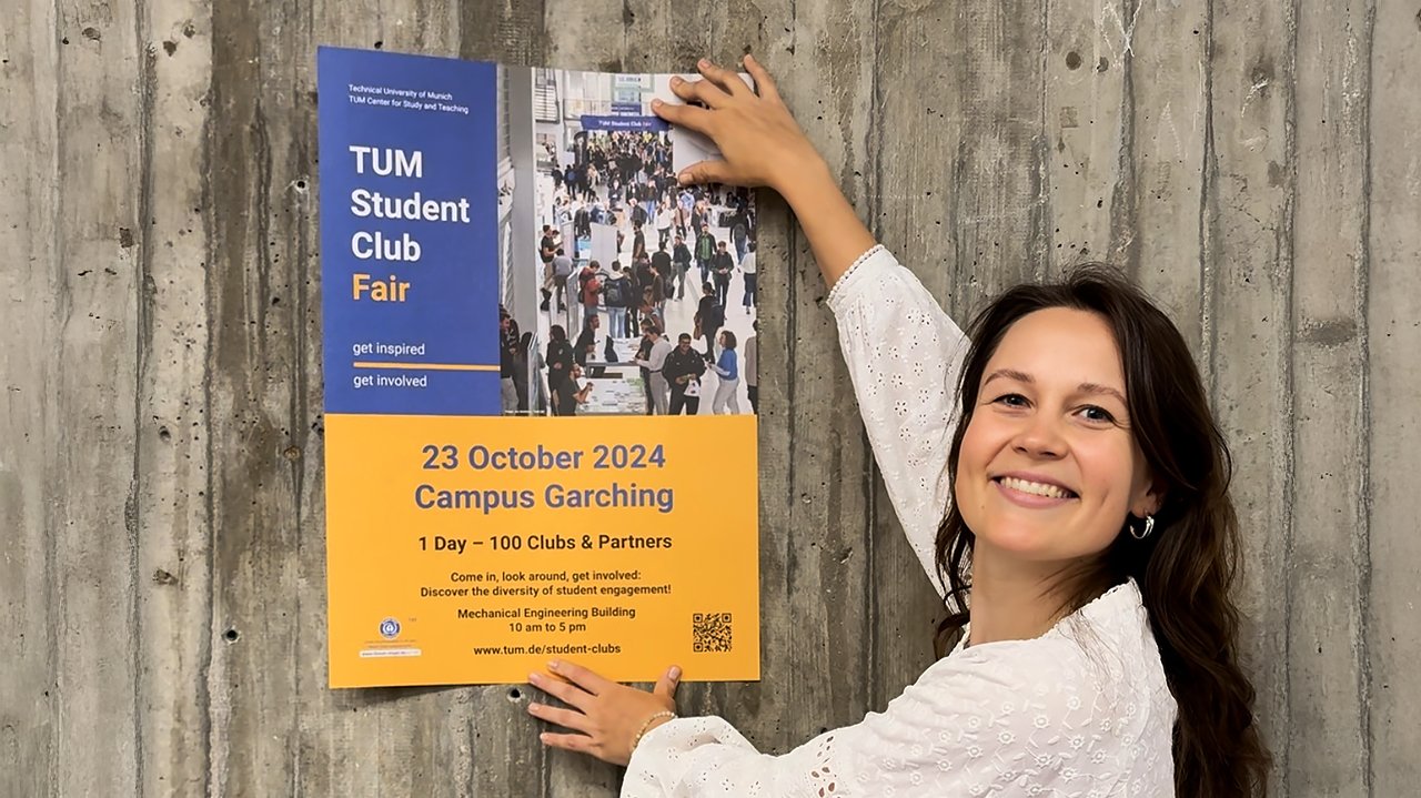 Anne Hüttenrauch vor einem Poster zu einer Studierendenmesse