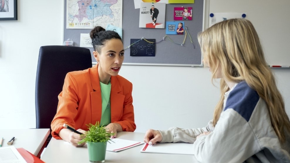 Eine Berufsberaterin berät eine junge Frau in ihrem Büro.