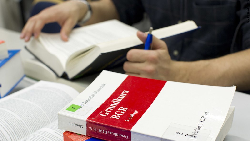 Auf einem Schreibtisch liegen mehrere verschiedene geöffnete und geschlossene Bücher neben- und auch aufeinander.
