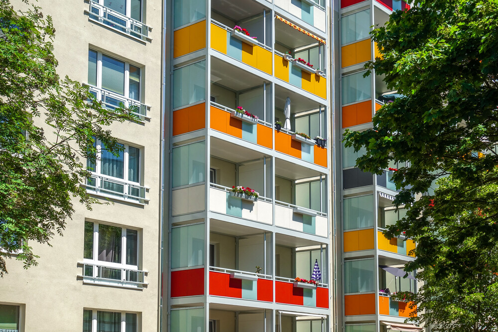Fassade eines Mehrfamilienhauses mit verschiedenfarbigen Balkonen.